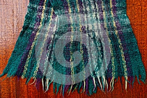 Part of a colored woolen scarf on a red table