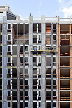 Fragment of the construction of a residential building using a construction cradle on a sunny day photo