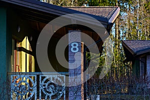 Fragment of the country cottage in the early morning in April. There pines and birches on the background with blue sky.
