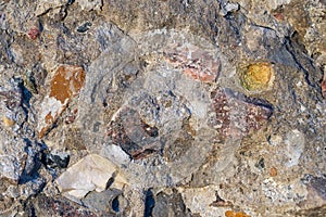 Fragment of a crumbling concrete wall with colorful crushed stone