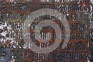 Fragment of Cyrillic Old Slavic letter on weathered stone slab on wall of ancient temple.