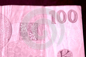 Fragment of a Czech banknote in one hundred crowns closeup. Money background pink color toned