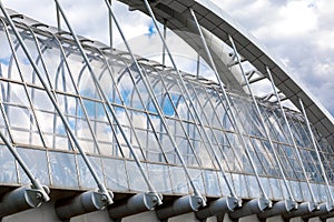 Fragment of an elevated pedestrian crosswalk. Arched support beam of a suspended pedestrian bridge with mounting elements against