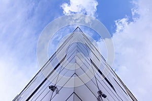 Fragment of the facade of abstract modern commercial architecture, the corner of the walls under a blue cloudy sky