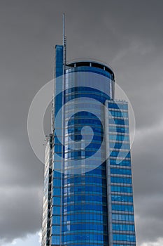 Fragment of the facade of a high-rise building, glass skyscraper on the background of thickening dark clouds,