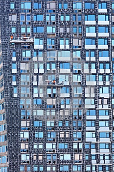 Fragment of the facade of a high-rise building under construction and its insulation using winches and mobile platforms, the