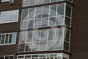 Fragment of the facade of a modern residential apartment building made of dark brown brick with windows and glazed loggias. photo