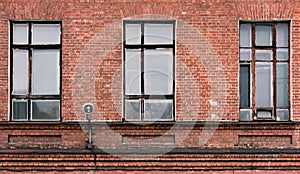 Fragment of the facade of an old brick building. High Windows and textural materials