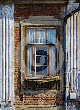 Fragment of the facade of an old brick house with a window and a drainpipe