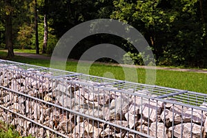 A fragment of a fence made of gabions. Separation of the street from the park area