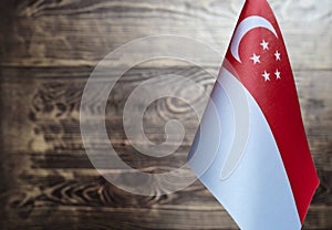 Fragment of the flag of the Republic of Singapore in the foreground blurred wooden background copy space