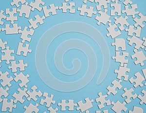 Fragment of a folded white jigsaw puzzle and a pile of uncombed puzzle elements against the background of a blue surface