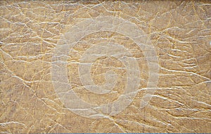 A fragment of genuine leather of high-quality workmanship with folds artificially painted in beige with a brown print photo