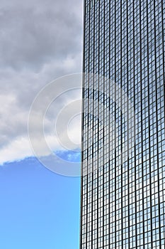 Fragment of the glass facade of a modern skyscraper against the sky