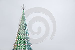 A fragment of a huge Christmas tree with many ornaments, gift boxes and luminous lamps. Photo of a decorated Christmas tree close-
