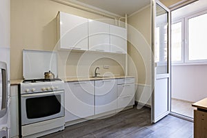 Fragment of the interior of a small kitchen with access to the balcony