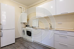 Fragment of the interior of a small kitchen with a fridge and a kitchen set photo