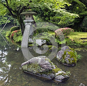 Fragment of japanese garden with stone lantern and big rocks covered with moss