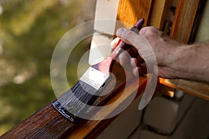 Fragment of a man`s hand with a paint brush. A man paints a window with varnish.