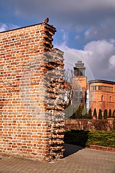 Fragment of a medieval defensive wall and red brick buildings