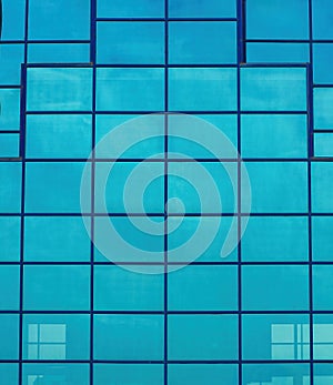 Fragment of a modern office building. Geometric background. Part of the facade of a skyscraper with glass windows.