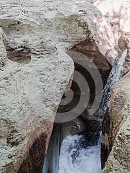 A fragment of a mountain waterfall flowing between relief smooth rocks