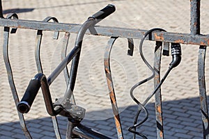 Fragment of an old bicycle fastened to an old lattice by a modern lock