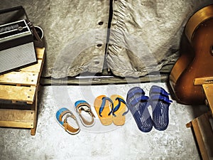 Fragment of an old camping tent with shoes standing in front of it, a guitar, a wooden bench and a radio on it