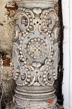 Fragment of an old column with a decorative pattern at the entrance to the church.