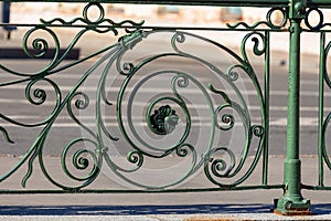 Fragment of an old elegant forged street fence. vintage green metal city fencing.