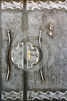 Fragment of an old metallic handmade door with doorknocker as ba