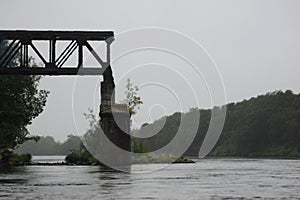 Fragment of the old railway bridge over the river in the fog