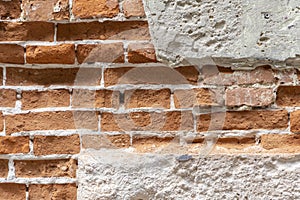 A fragment of old red brick masonry in the plastered facade of the building. Concept: renovation and cladding of old buildings.
