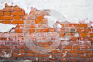 Fragment of old red brick wall with destructed stucco coating.