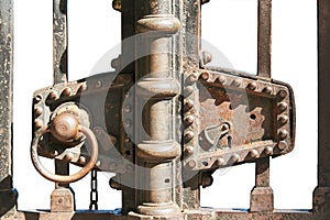 Fragment of old, rust-covered metal gates with a lock