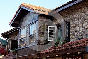 Fragment of an old stone house with wooden shutters and windows