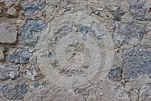 Fragment of an old stone wall, on the surface of the destruction and cracks