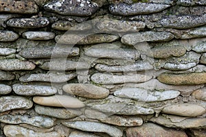 Fragment of an old wall of gray stone blocks. The stones are flat and rough. Background. Texture