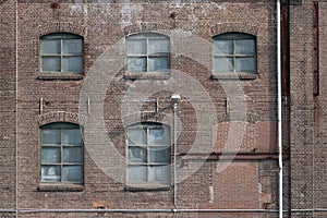 A fragment of an old and weathered facade of an old factory, made of masonry, steel and wooden frames