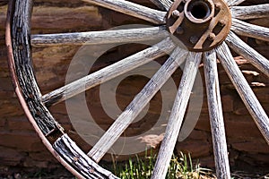 Fragment of the old wheel near a stone wall