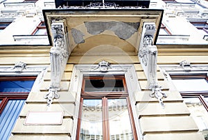 Fragment starého okna a balkóna s karyatídami.