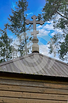 Fragment of an old wooden Christian church with a cross on the background of sky
