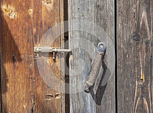 A fragment of an old wooden door with a rusty bolt and handle