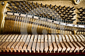 Fragment of open upright piano mechanism with strings and hammers