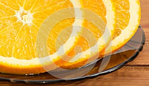 Fragment of orange slices on a glass saucer closeup