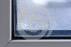 A fragment of a plastic window with condensation of water on the glass. Concept: defective plastic window with condensation,