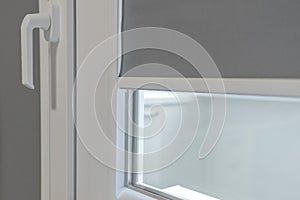 A fragment of a plastic window. PVC window with lowered roll-up blinds