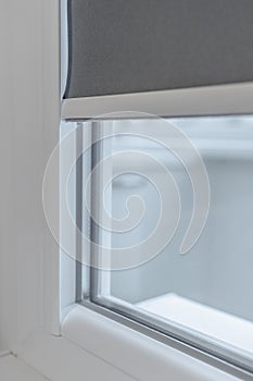 A fragment of a plastic window. PVC window with lowered roll-up blinds