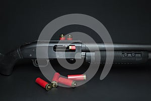 Fragment of a pump-action shotgun with cartridges on a black background.