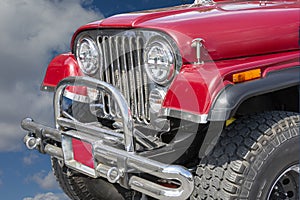 Fragment of a red jeep against white clouds